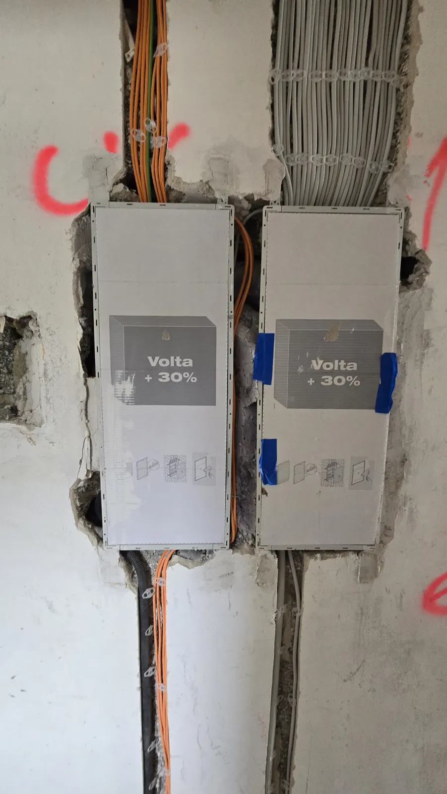 Zwei eingebaute Unterverteilungen in einer Wand mit zahlreichen zugeführten Leitungen