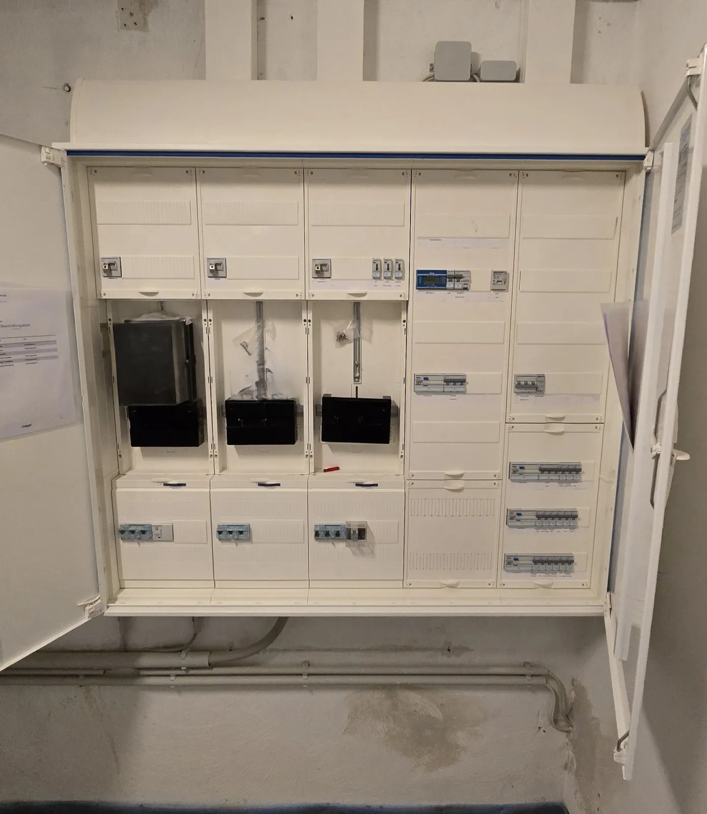 Geöffneter Zählerschrank mit mehreren Zählerplätzen und Sicherungsautomaten