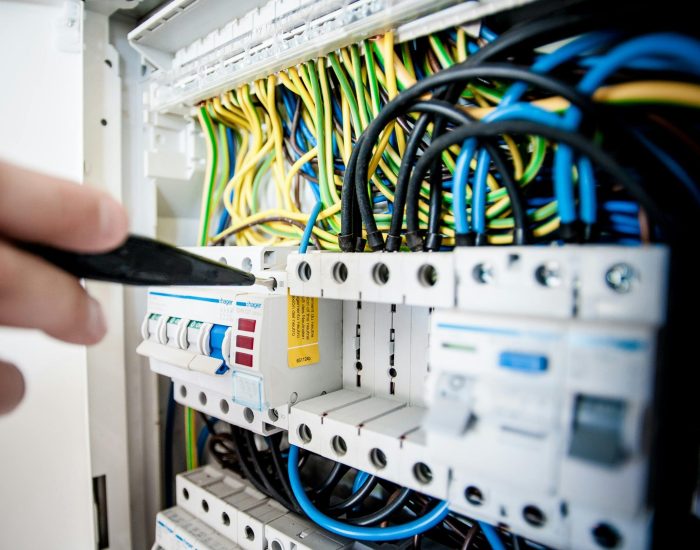 pexels-photo-257736-257736 Hand of electrician working on a circuit breaker panel with colorful wires, ensuring safe electrical connections.